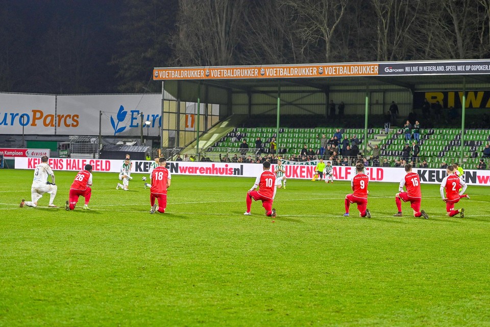 Spelers van FC Dordrecht en MVV knielen op de grasmat als actie tegen racisme. 
