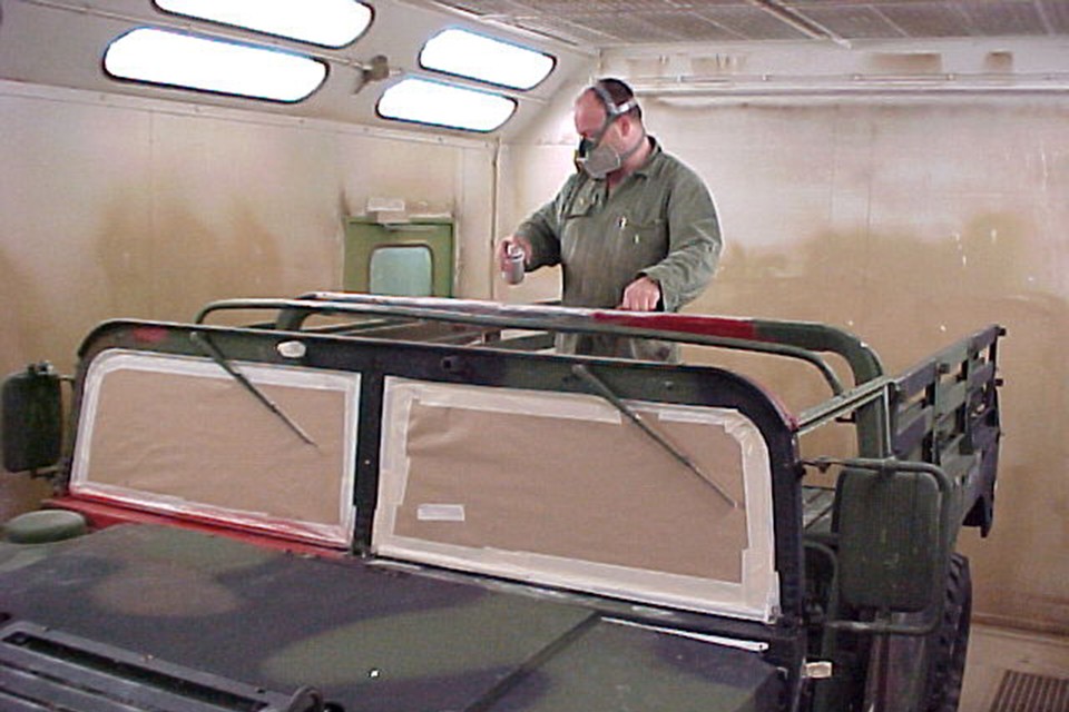Een medewerker gebruikt chroom6-verf om een legervoertuig over te spuiten. 