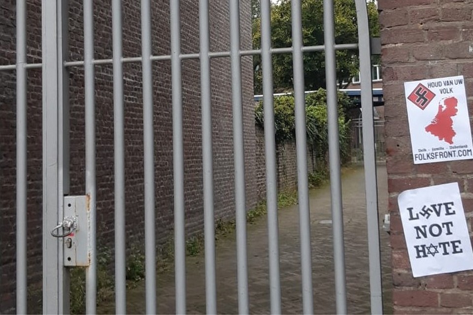 Op een muur naast de poort naar het kantoor van Vluchtelingenwerk Maastricht hingen twee nazi-plakkaten. 