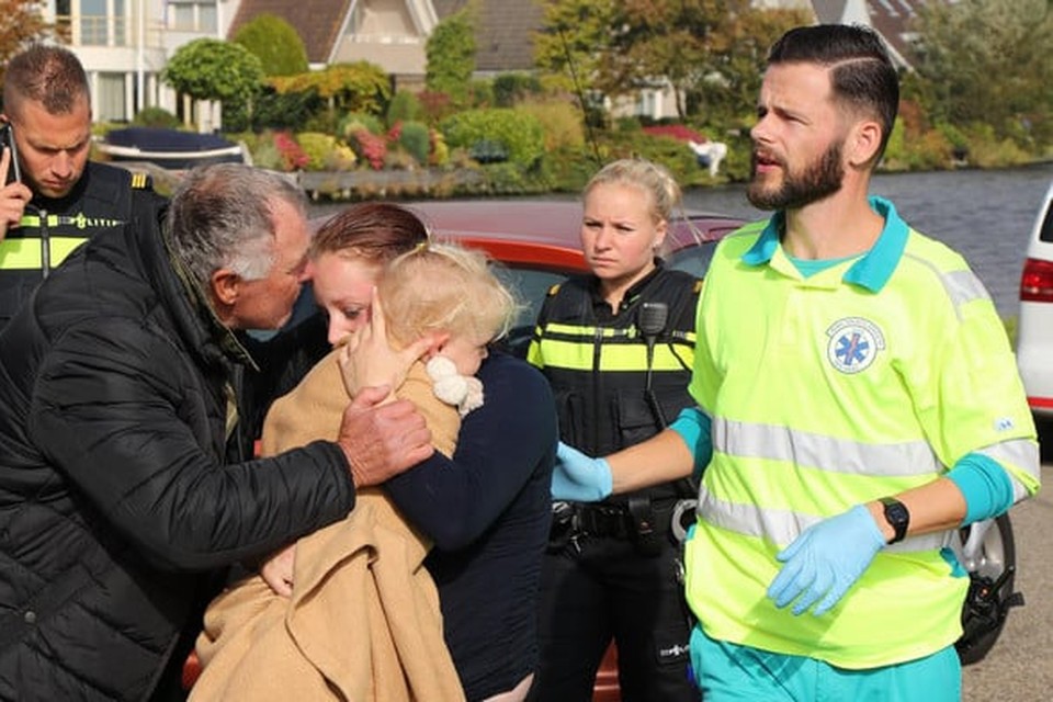 Visser André Krens troost de in het water gereden moeder en kind.