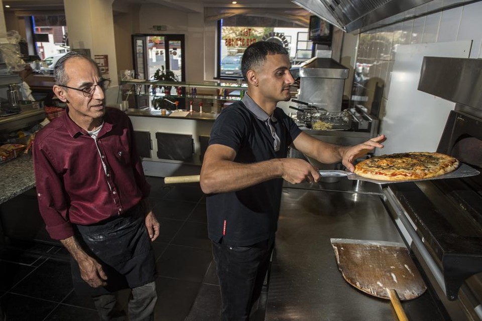 Hawbir Moustafa bakt onder het toeziend oog van zijn vader een pizza in zijn restaurant Mamma Mia. 