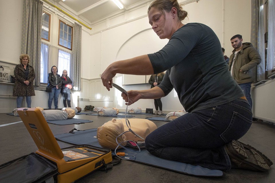 Een medewerkster van de AED-leverancier laat buurtbewoners van het station in Weert zien hoe het apparaat werkt en iemand met een hartstilstand snel kan worden geholpen. 
