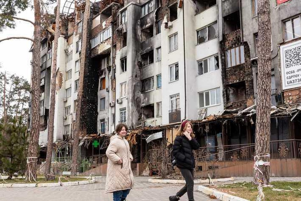Vrouwen lopen langs een verwoest gebouw in Kiev.