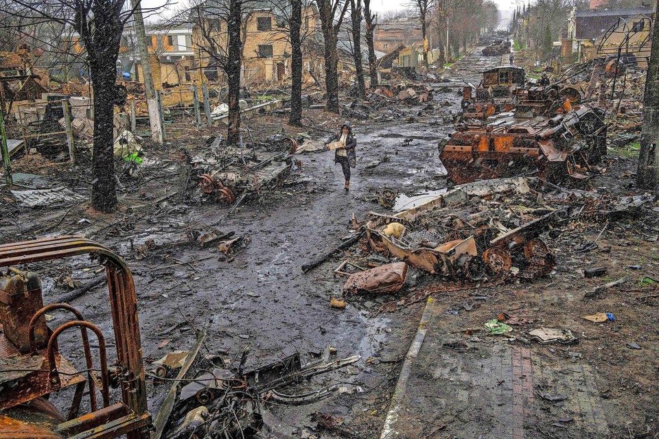 Een vrouw loopt door een compleet verwoeste straat in Boetsja.