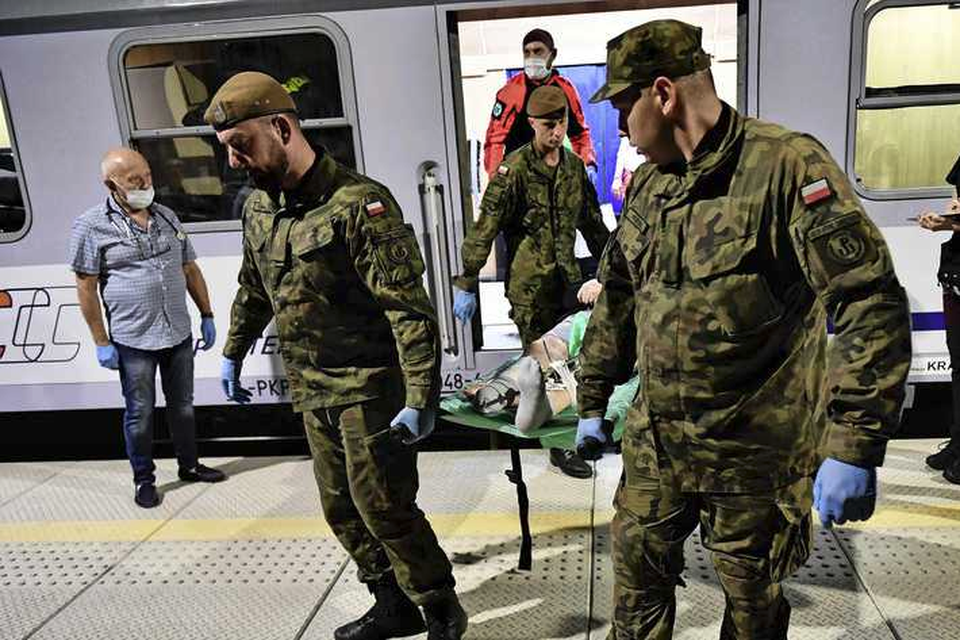 Poolse soldaten halen een gewonde collega uit Oekraïne na aankomst in Wroclaw van een speciale trein af. 