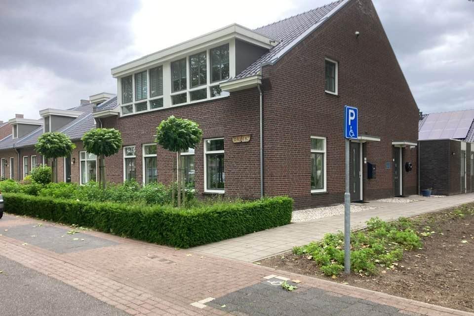 Het gebouw van het huiskamerproject in Afferden met rechts de invalidenparkeerplaats. 