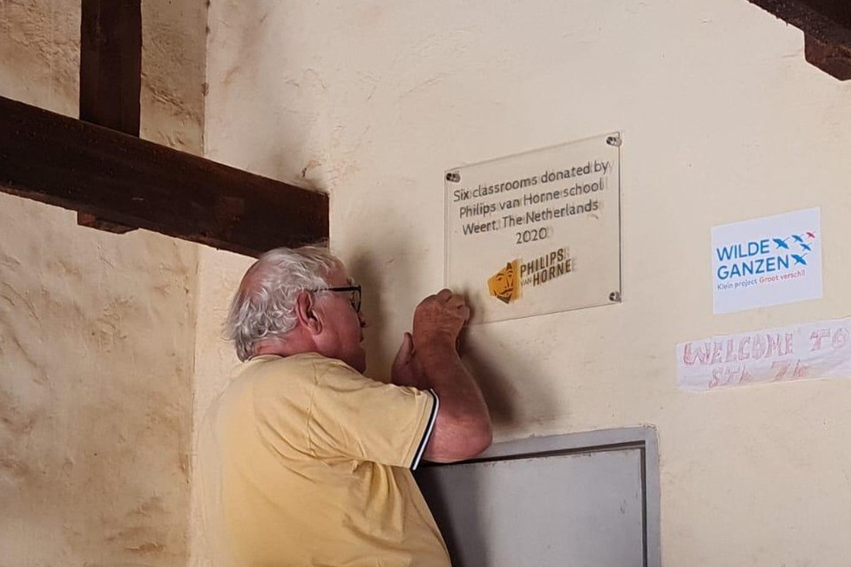Pater Jo Kuppens bevestigt een plaquette in een klaslokaal in Malawi die verwijst naar de donatie van Scholengemeenschap Philips van Horne in Weert. 