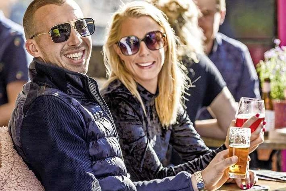 Maikel en Diana uit Oisterwijk genieten op het terras van een biertje. „Het zonnetje doet echt iets goeds met je geest.” 