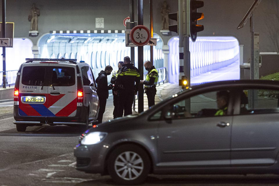 De politie controleert een jongeman bij de stationstunnel in Roermond als maandagavond de avondklok is ingegaan. 