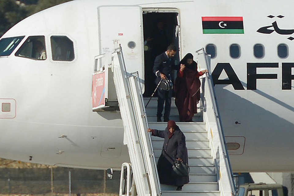Bemanningsleden van de gekaapte Libische Airbus A320 helpen passagiers uit het toestel.