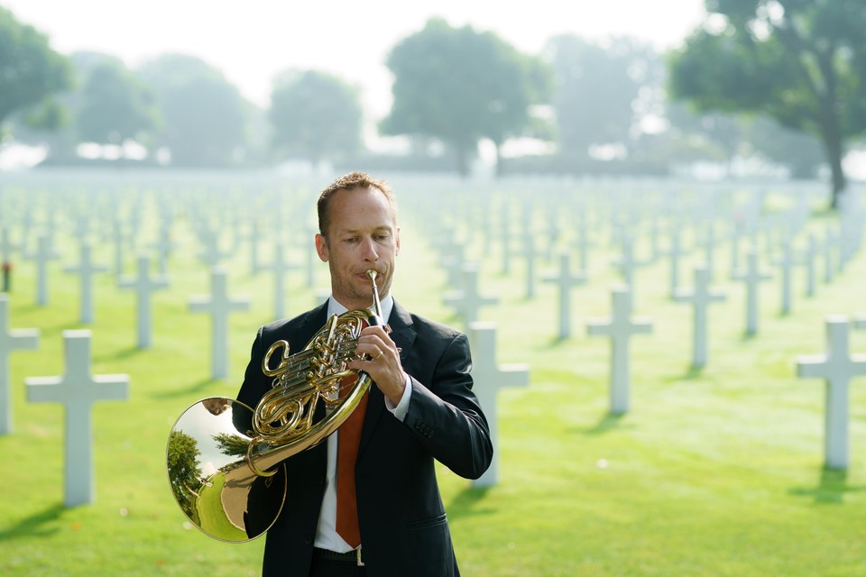 Hoornist Cleo Simons van de philharmonie zuidnederland speelt de hymne ‘Unknown Territory’ op de Amerikaanse begraafplaats in Margraten. 