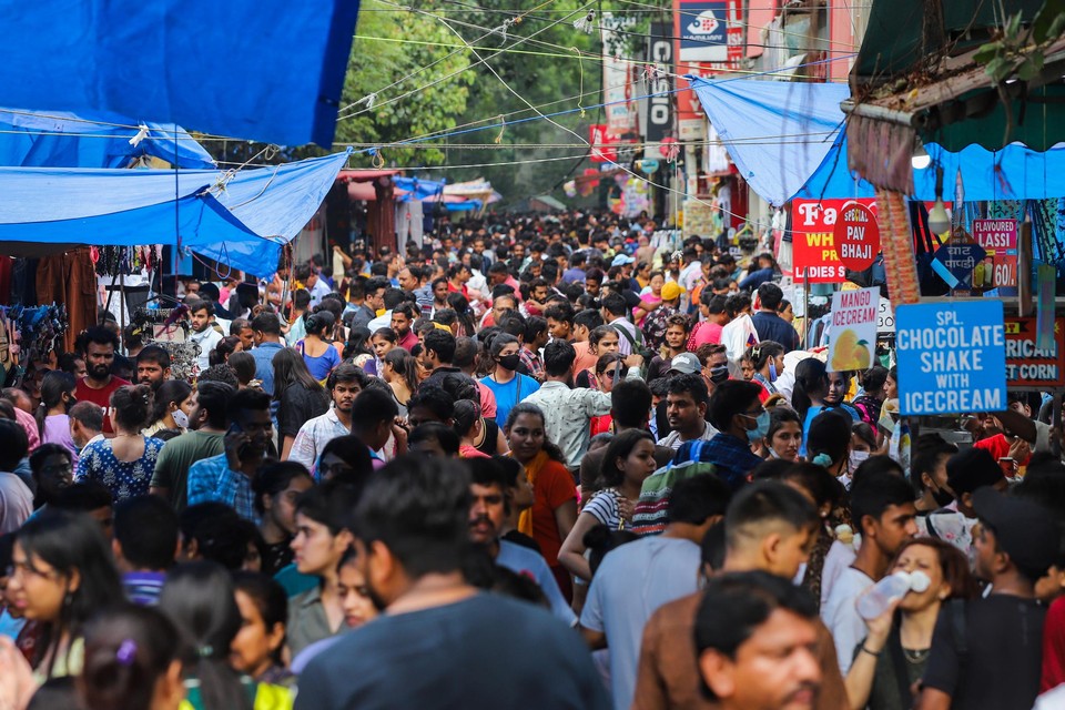 Winkelende mensen op een markt in New Delhi. India haalt China straks in als land met de grootste bevolking ter wereld. 