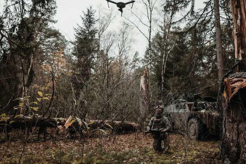 Snorrend schiet een muisgrijze Atlas-drone omhoog tussen de bomen. 