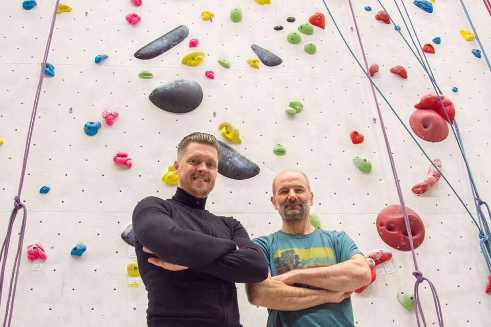 Tim Mullens (links) en Geert Voncken voor een klimwand vol gekleurde klimgrepen. 