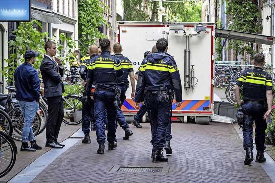 Agenten lopen bij de afzetting in de Lange Leidsedwarsstraat in Amsterdam waar op 6 juli vorig jaar een aanslag werd gepleegd op Peter R. de Vries. 