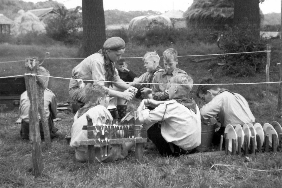 Jonge leden maken op een houtvuur een gerecht (1954). 