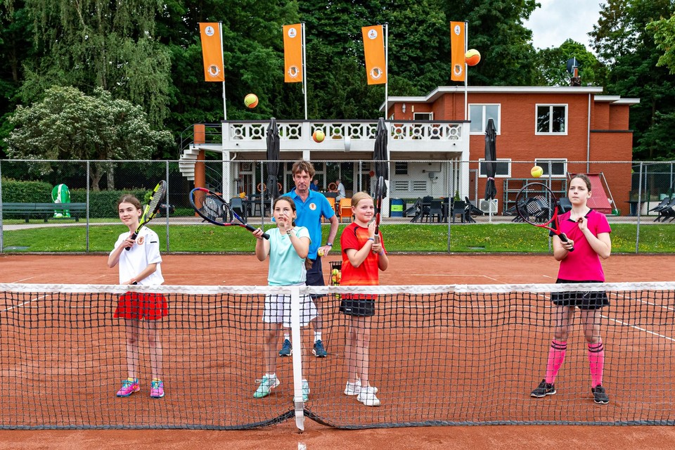 Trainer Rob van Oppen geeft les aan groepje jeugdige tennissers.  