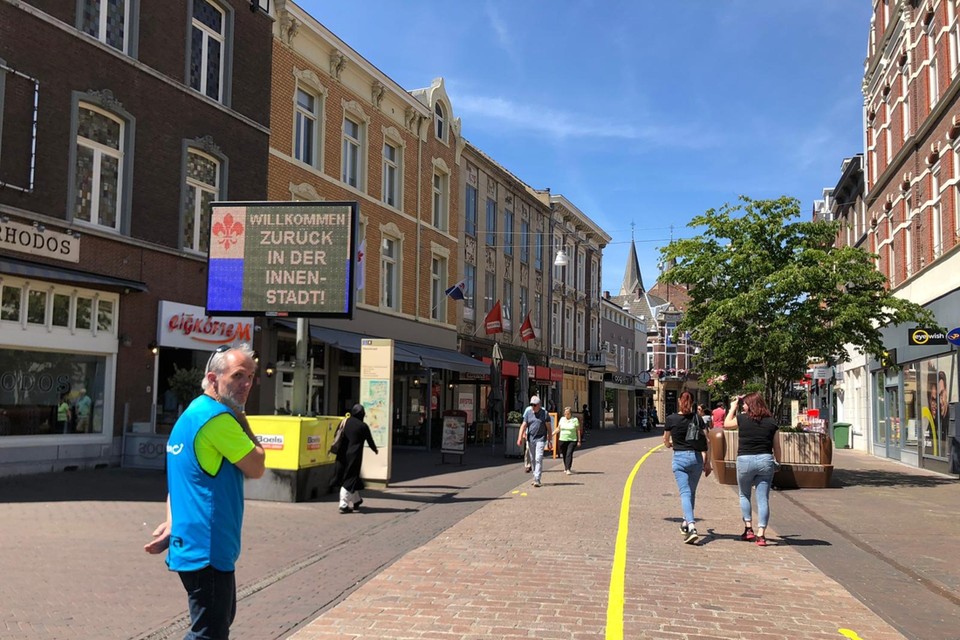 Op de winkelstraat in de stad is een geel lint gelegd om ervoor te zorgen dat het winkelend publiek niet door elkaar heen loopt. 