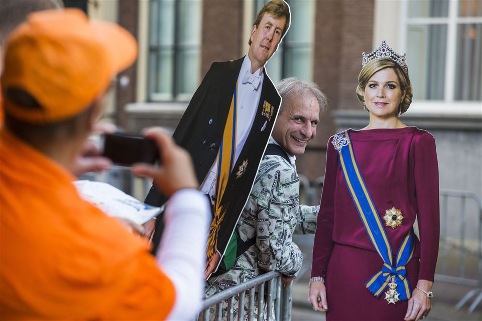 Oranjefan Johan Vlemmix poseert met twee kartonnen afbeeldingen van koning Willem Alexander en koningin Maxima op Prinsjesdag bij paleis Noordeinde.