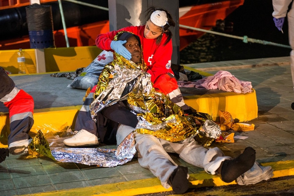Een medewerker van het Spaanse Rode Kruis bekommert zich om een van migranten. 