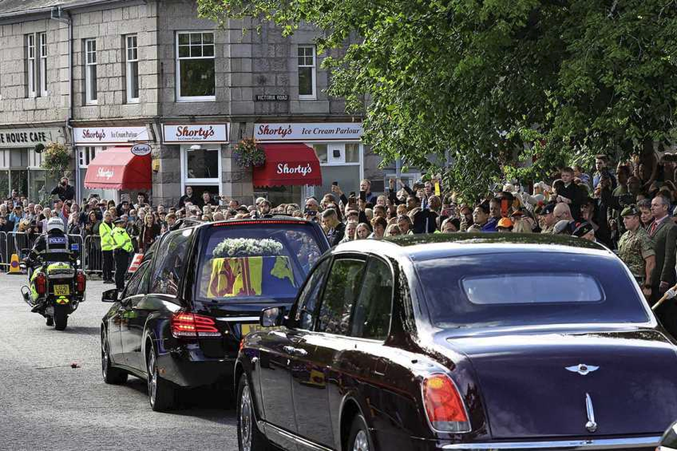 De rouwstoet, met zichtbaar de kist van koningin Elizabeth bedekt met de koninklijke standaard van Schotland, rijdt door het dorpje Ballater. 