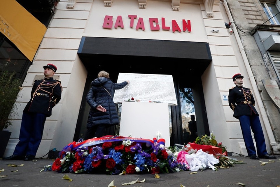 De herdenking op 13 november 2018 van de aanslagen in Parijs, drie jaar eerder. Er zijn bloemen neergelegd voor de Bataclan-concerthal. Een vrouw raakt de gedenkplaat aan. 