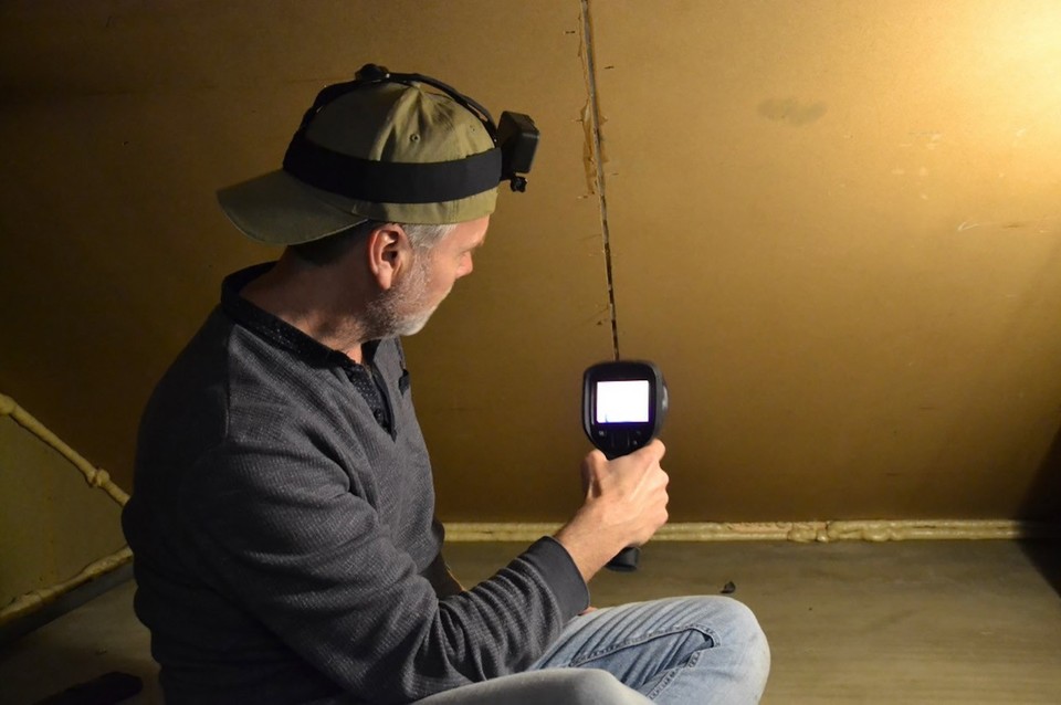 Lars Boelen onderzoekt met een infraroodcamera tochtplekken op zolder. 
