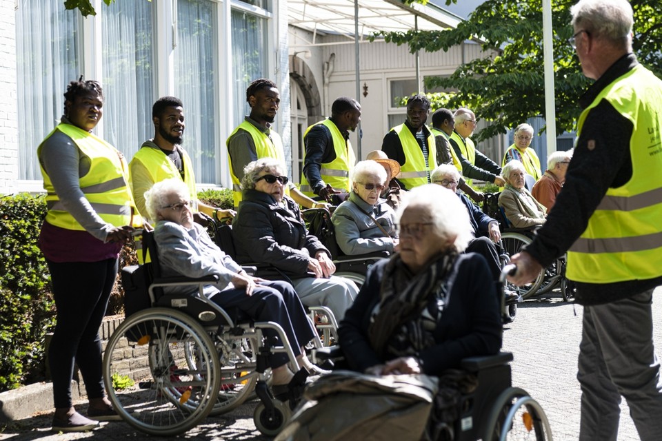 Asielzoekers wandelen met ouderen van zorgcentrum St. Elisabeth in Haelen. 