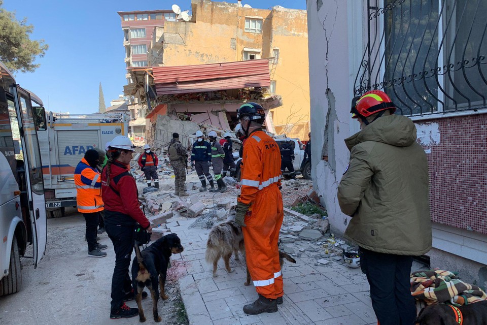 Reddingswerkers van het Nederlandse reddingshondenteam RHWW wachten vanaf een afstandje op hun inzet bij een van de  zoekacties in een woonwijk van Antakya.