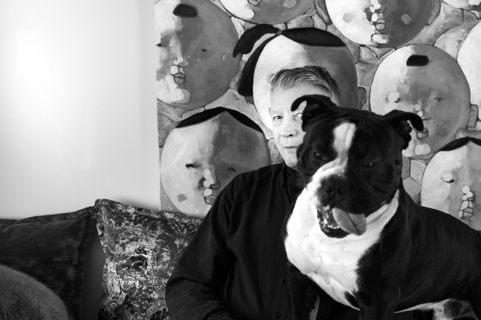 Peter Wauben met zijn hond voor een schilderij met vele gezichten. 