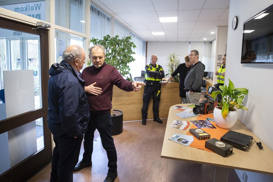 Bestuurder Hubert Hermans (l.) van BieOs wordt door vrijwilliger Frank Ivens richting de bestuurskamer gemaand, onder toeziend oog van de opgetrommelde politie.