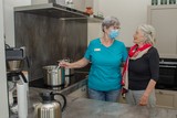 thumbnail: Jeannette de Bie in de keuken van Maison Molenbeecke met bewoonster Ineke. Op de tweede foto is ze aan het werk in de broodjescorner. 