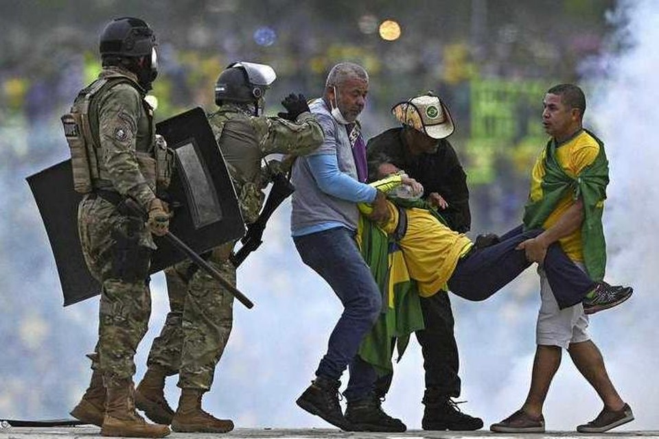 Een Bolsonaro-aanhanger wordt weggevoerd.