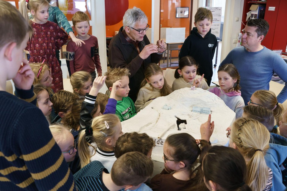 Leerlingen van de Schinnense basisschool Sint Dionysius luisteren naar de uitleg van Pierre Habets (midden) en Raymond Brouwers (rechts) bij het ontwerp van de maquette van de verdwenen watermolen.