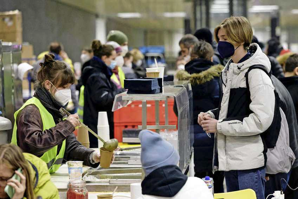 Een vrijwilliger deelt voedsel uit aan Oekraiense vluchtelingen die op het Hauptbahnhof in Berlijn zijn aangekomen. 