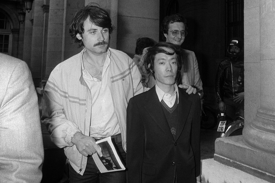 Een Franse politieman in burger voert de Japanse moordenaar Issei Sagawa in 1981 mee in het hoofdbureau van politie in Parijs. 