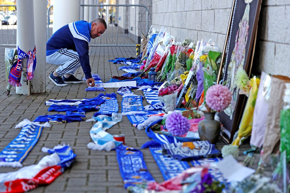 Een Leicester City-fan legt een sjaal bij het voetbalstadion nadat bekend is geworden dat clubeigenaar Vichai Srivaddhanaprabha is omgekomen bij de heli-crash. 