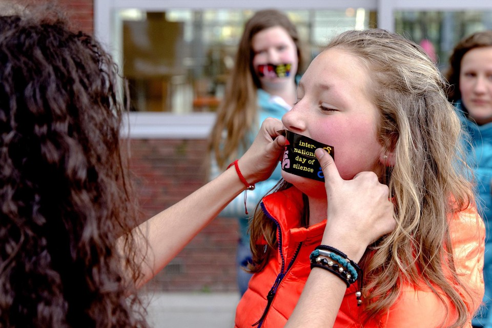 Een leerling plakt een sticker op de mond van een medescholier in het kader van de International Day of Silence, een antipestdag die op 400 scholen plaatsvindt. 