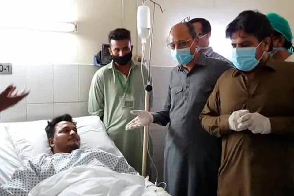 Mohammed Zubair ligt in een ziekenhuis in Karachi. Hij overleefde de vliegtuigcrash. Om hem heen staan enkele hoogwaardigheidsbekleders, onder wie minister Saeed Ghani van de provincie Sindh (tweede van rechts, met bril).