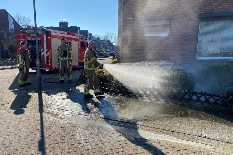Brandweerlieden spuiten de stoep schoon. 