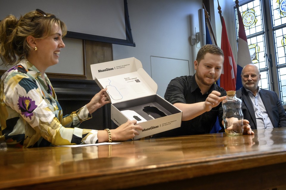 Kunstenaar Sjang Niederwieser (midden) toont zijn winnende ontwerp MaasGlaas. Links wethouder Viviane Heijnen met de door MTB vervaardigde doos. 