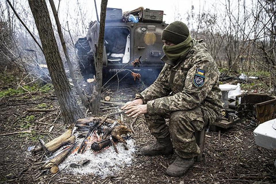 Een Oekraïense soldaat probeert op te warmen aan de frontlinie. 