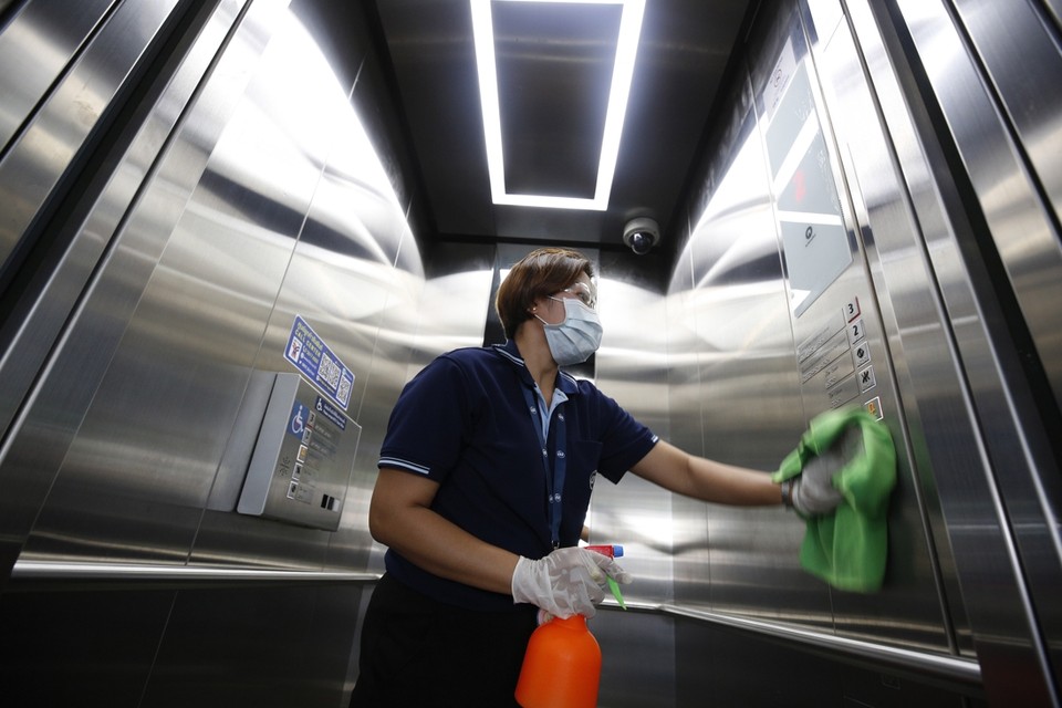 Een schoonmaker desinfecteert een lift op een station in de Thaise hoofdstad Bangkok. 