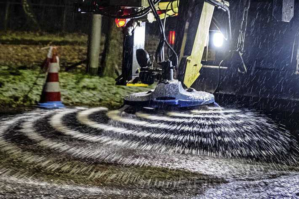 Medewerkers van Rijkswaterstaat maken een strooiwagen gereed met strooizout.