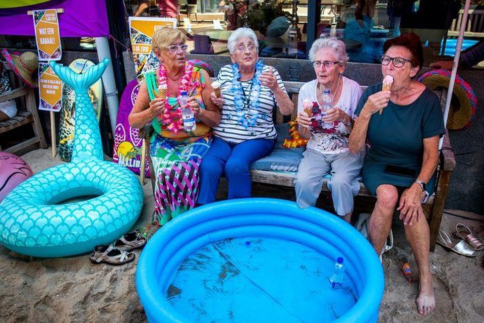 Ouderen van een zorgcentrum genieten van het zomerse weer. Om de bewoners vanwege de aanhoudende hitte wat verkoeling te geven is er een strandje aangelegd. 