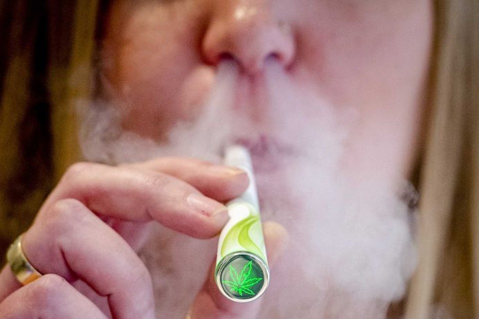 Een vrouw rookt een elektronische sigaret met cannabissmaak. 
