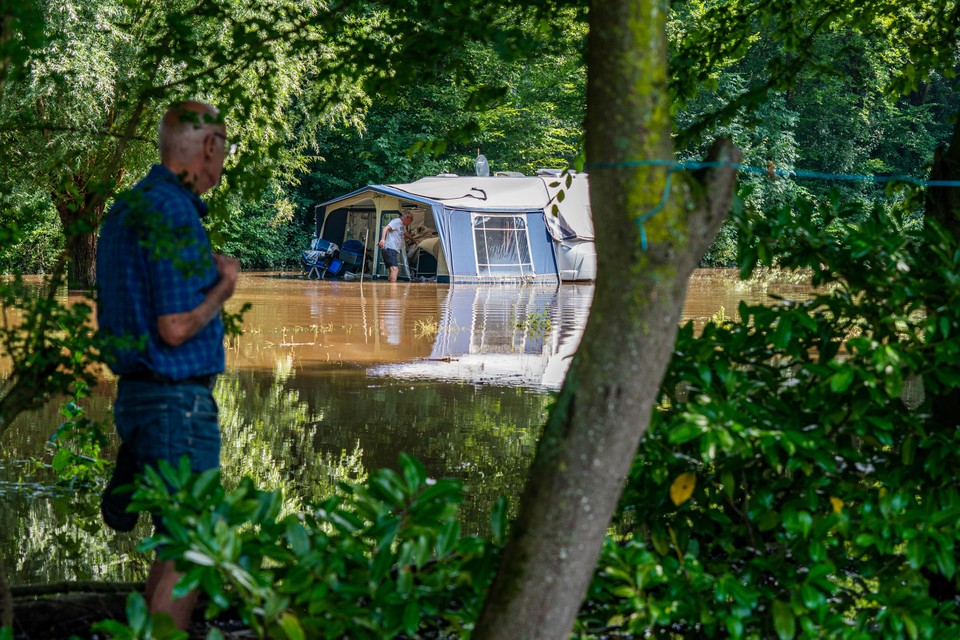 John Maens (op de achtergrond) uit Maastricht probeert, tegen beter weten in, te redden wat er nog te redden valt in zijn caravan op camping De Boskant. 
