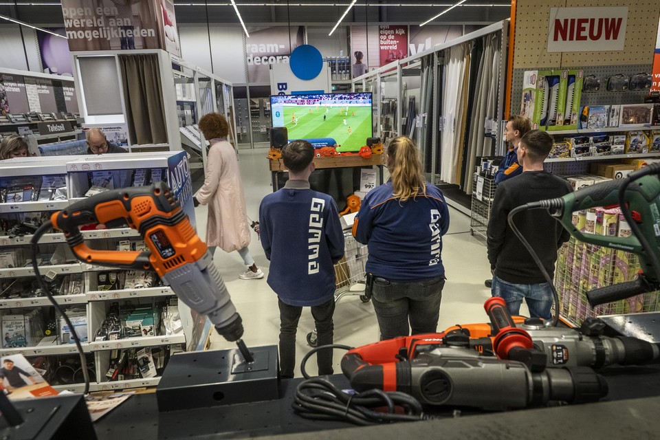 Personeel en klanten van de Gamma in Maastricht kijken op een showmodel van een tv-scherm naar Oranje. 