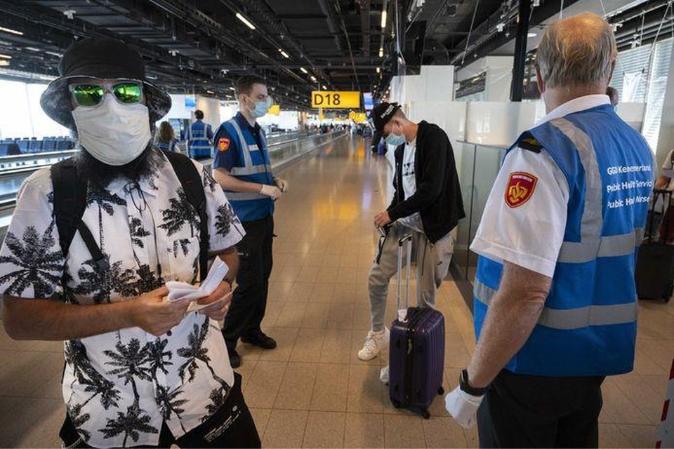 Medewerkers van de GGD ondervragen reizigers op luchthaven Schiphol. 