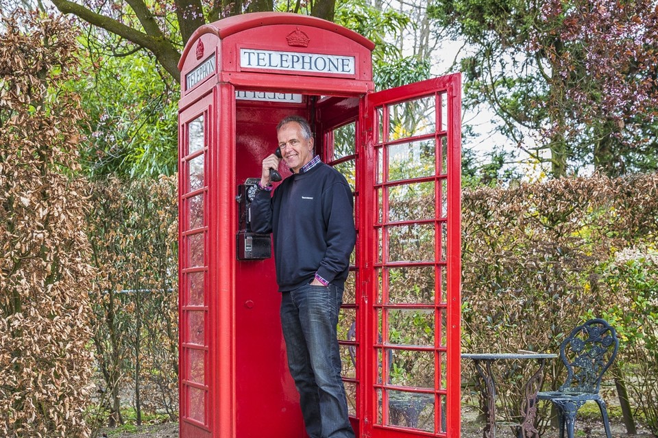 Nico Janssen bij de Britse telefooncel in zijn tuin. 